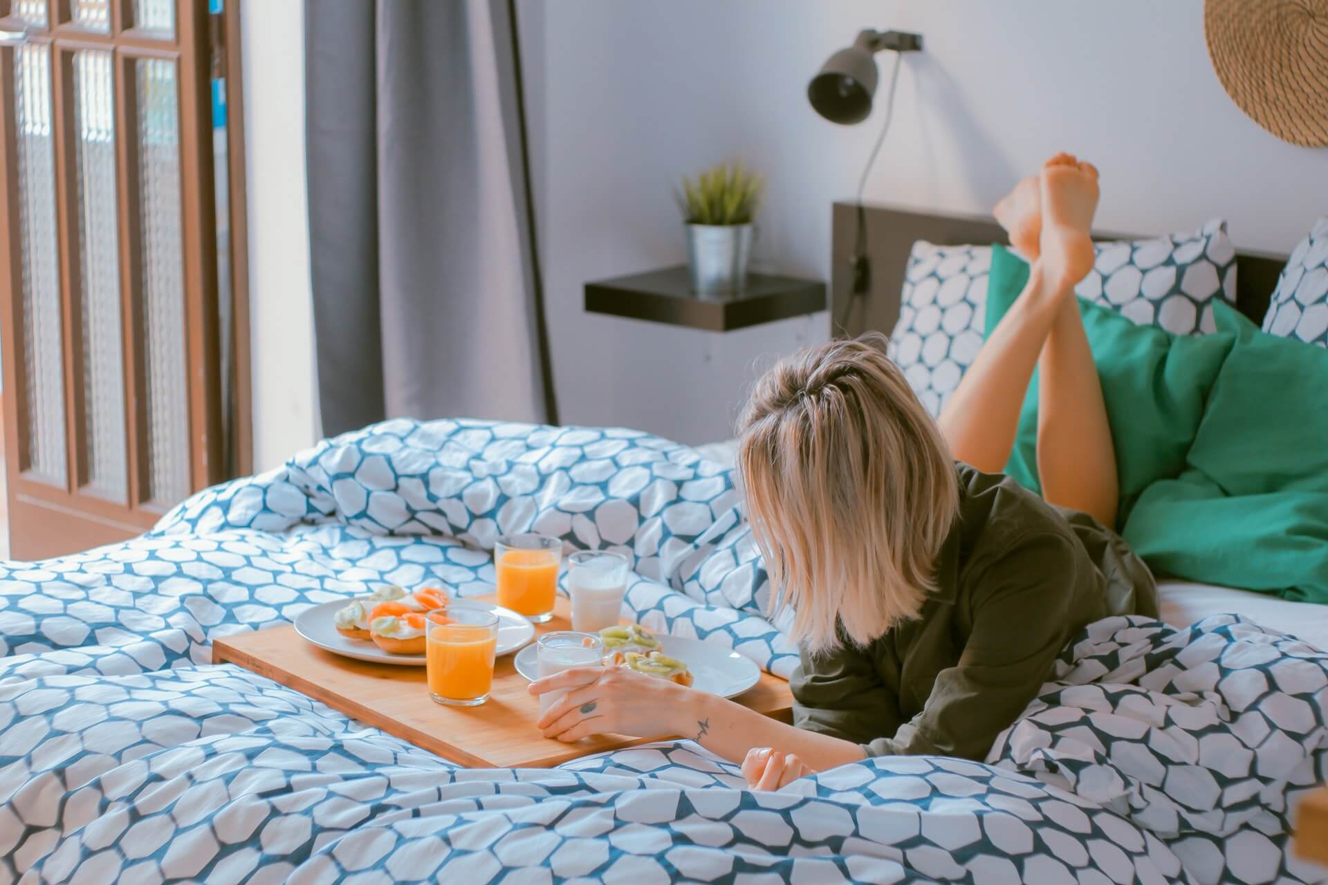 Woman relaxing on bed with breakfast